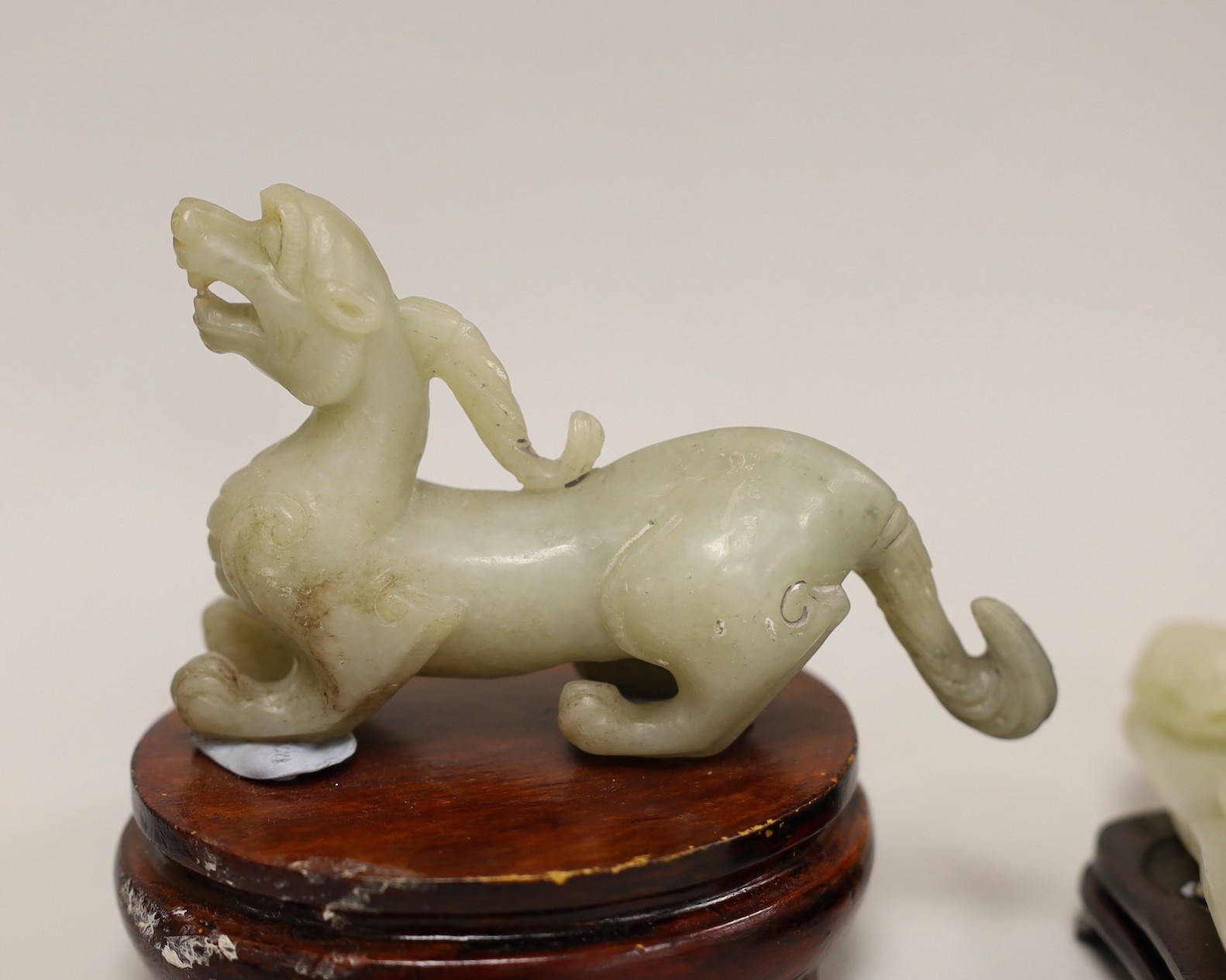 A Chinese pale celadon and grey jade mythical beast on stand and a pale celadon jade belt hook, mythical beast 11cms wide